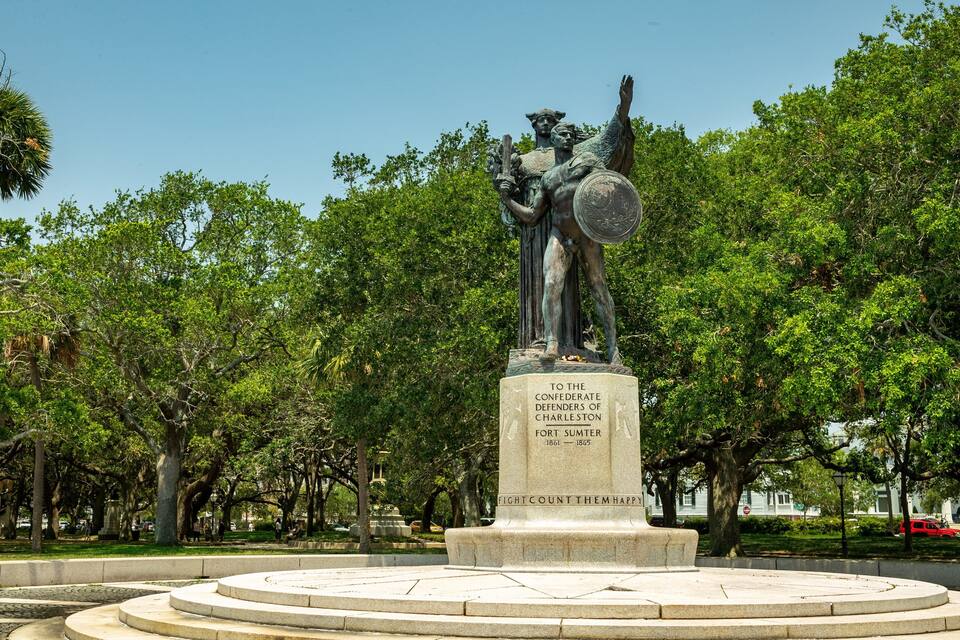 Una estàtua confederada en un parc amb arbres i una base de pedra circular.