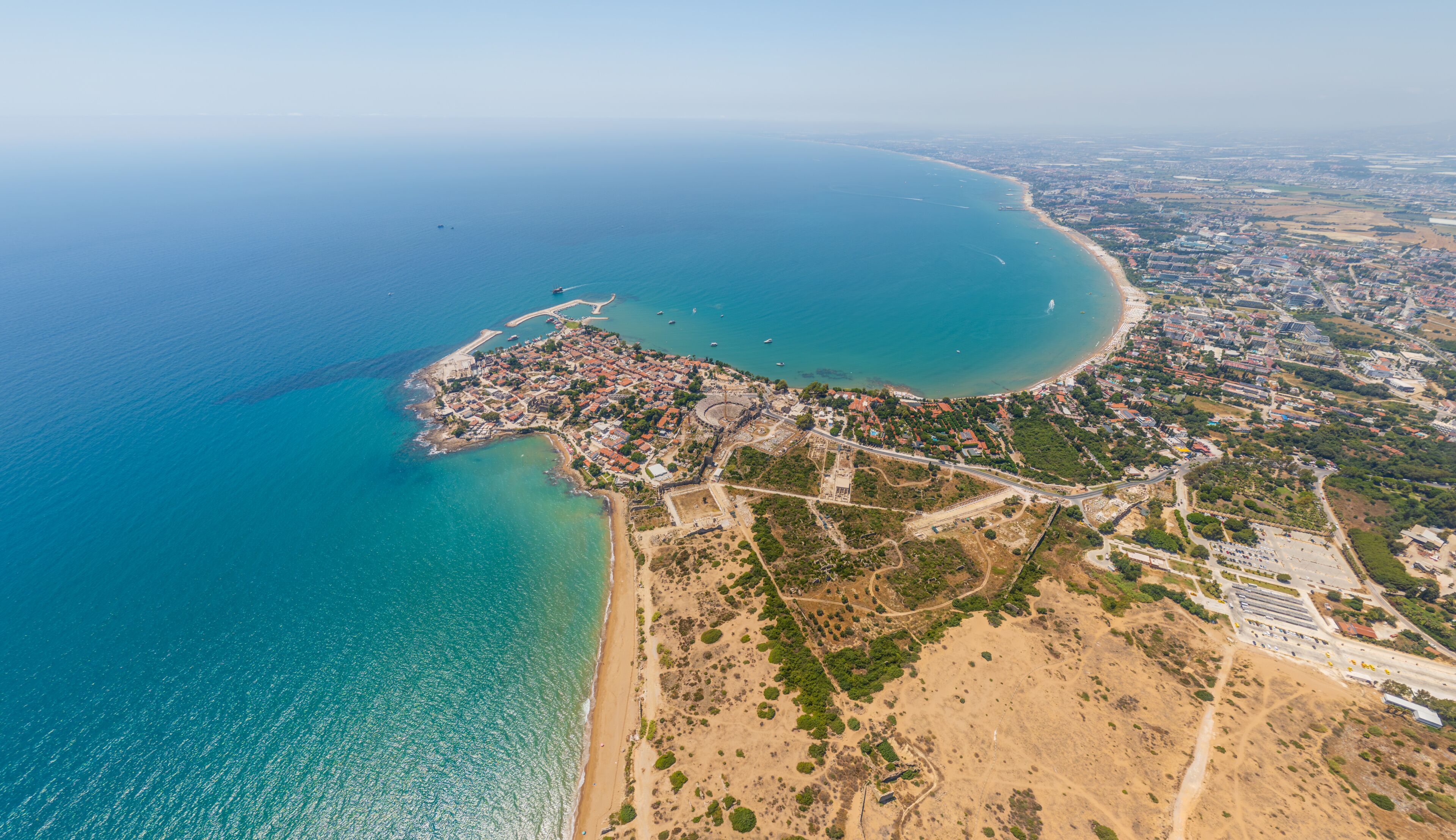 Side, Manavgat, Turkey. Aerial panorama of modern Side town, Mediterranean coastline and ancient peninsula excavations on sunny summer day. Aerial view