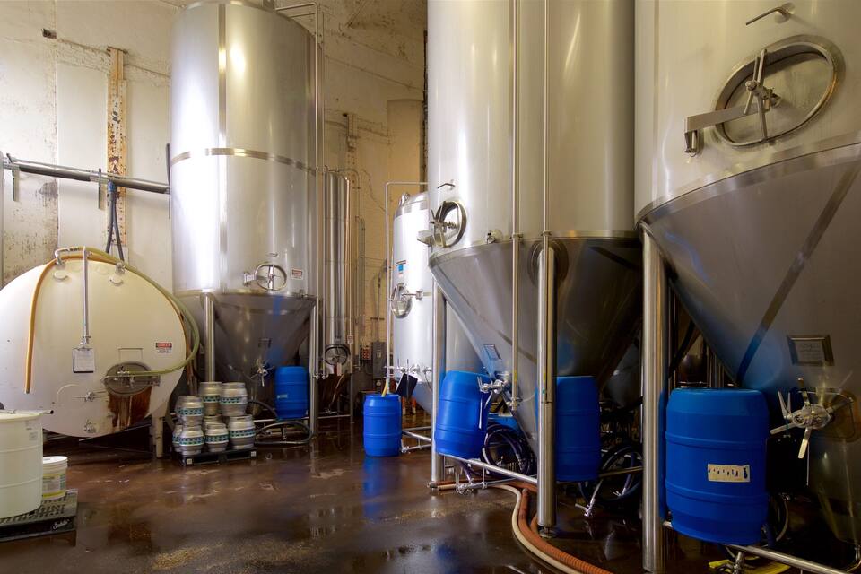 A brewery with stainless steel tanks and blue barrels.