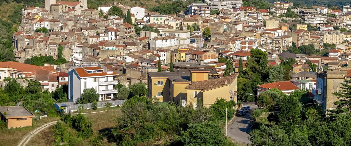 A town with historic buildings, a prominent tower, and a hilly backdrop.