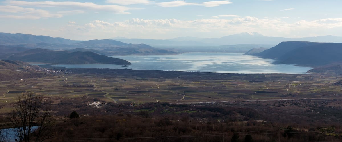 A panoramic view of a lake surrounded by mountains and valleys.