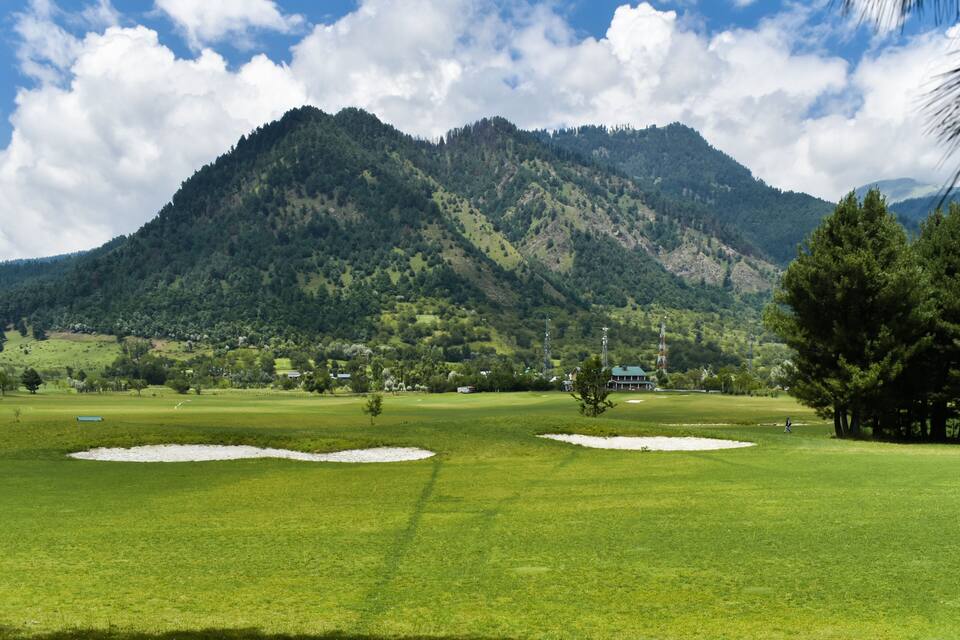 Camp de golf amb búnquers de sorra, una muntanya al fons i un cel serè.