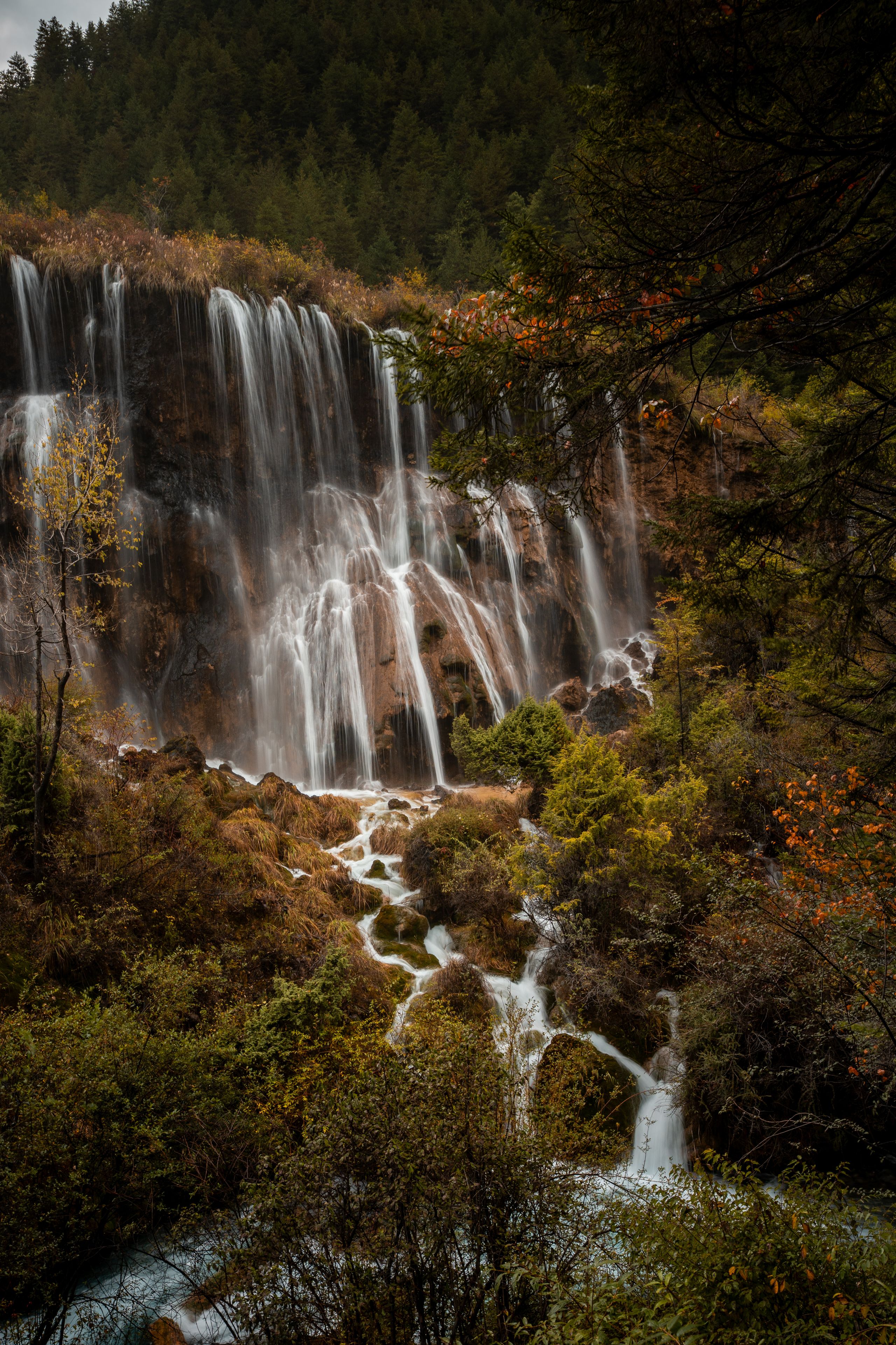 A waterfall cascading over rocks surrounded by autumn foliage.