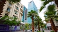 A city street with tall buildings, palm trees, and a sign for a tourist center.