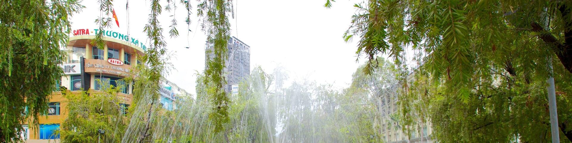 A fountain surrounded by greenery and buildings.