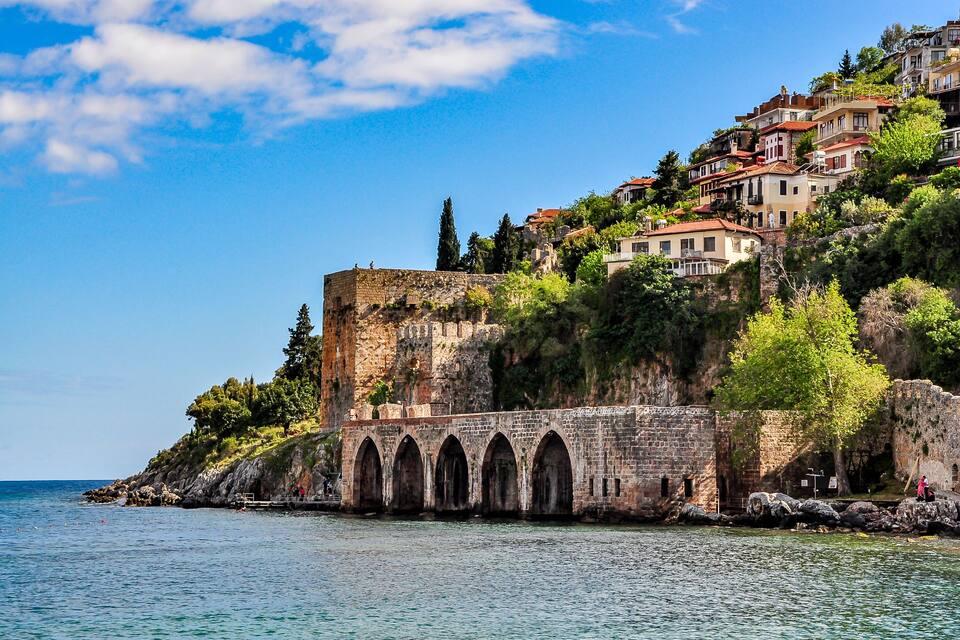 A coastal town with historic stone buildings, a prominent castle, and a clear blue sky.