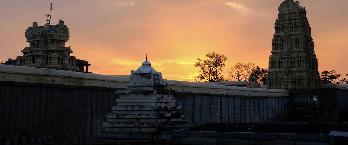 A temple complex with intricate carvings and a sunset sky.
