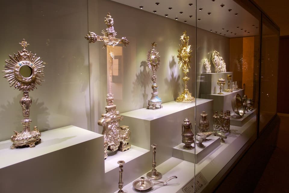 A display of ornate silver religious artifacts in a museum.