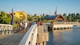 A pedestrian bridge over water with a wooden pavilion and a sign reading "WELCOME TO PERCIVAL LANDING".