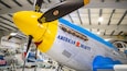 Un aereo con la scritta 'American Beauty' sul lato, un'elica e una combinazione di colori blu e giallo.