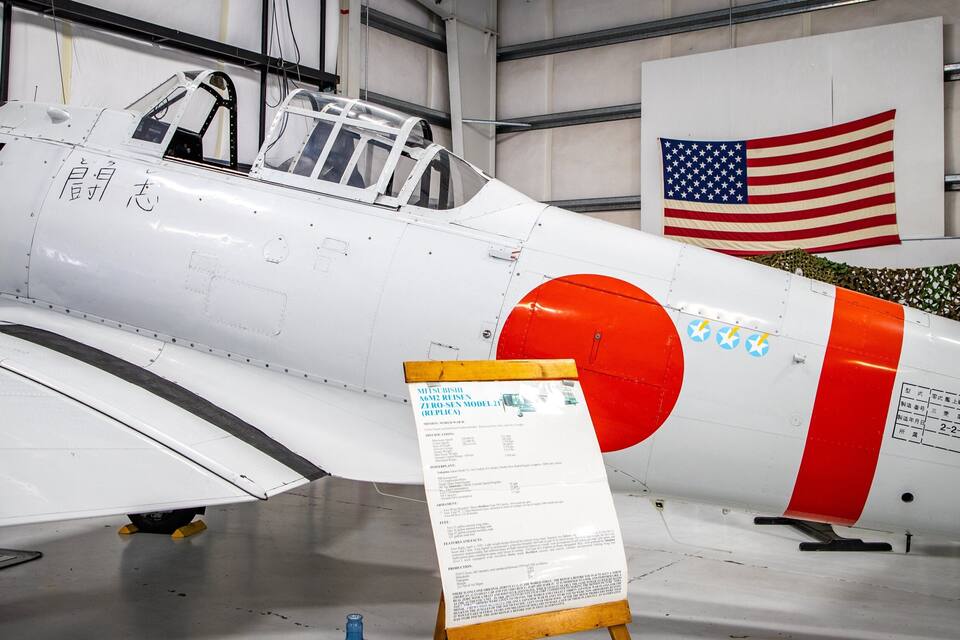 A white and red vintage aircraft with a detailed placard in front.