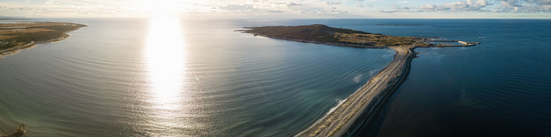 Aerial panoramic view of a scenic road during a vibrant sunny sunset. Taken in Cow Head, Newfoundland, Canada.