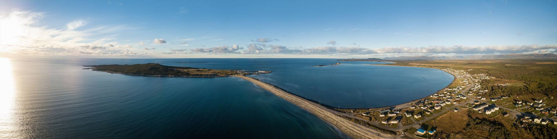 Aerial panoramic view of a small town on the Atlantic Ocean Coast during a vibrant sunny sunset. Taken in Cow Head, Newfoundland, Canada.