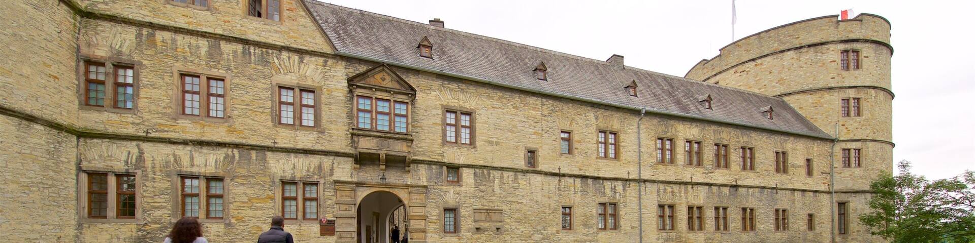 A historic stone building with a courtyard and a flag on top.