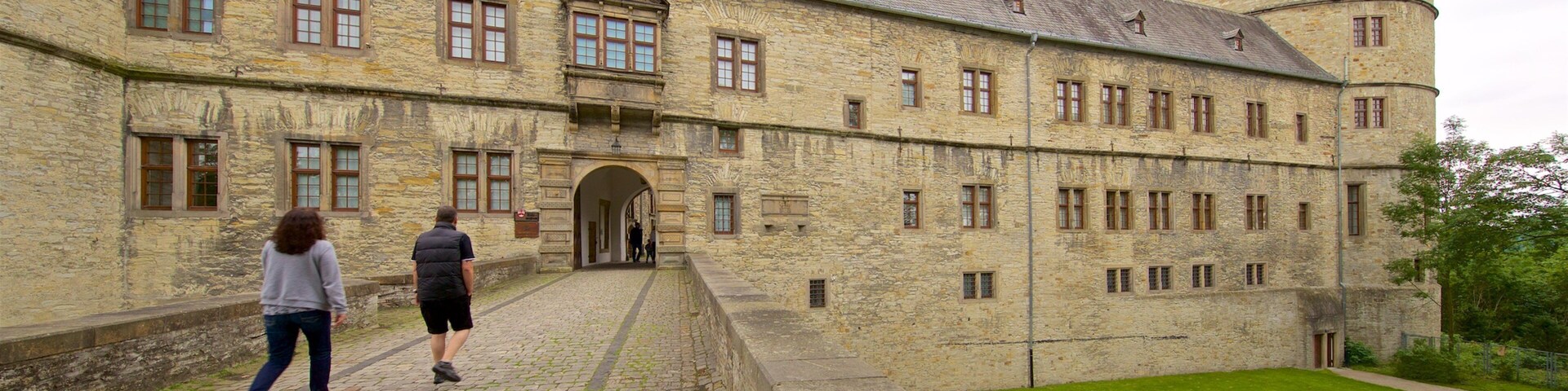 Un edificio histórico de piedra con un patio interior y una bandera en la parte superior.