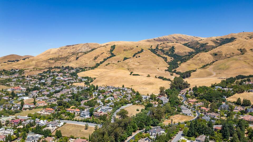 Drone photo of Mission Peak in Fremont, California on a beautiful summer day, with dead hills and houses at the base of the mountain.