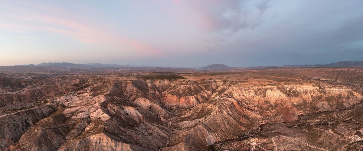 A rugged mountainous landscape with winding roads and sparse vegetation.