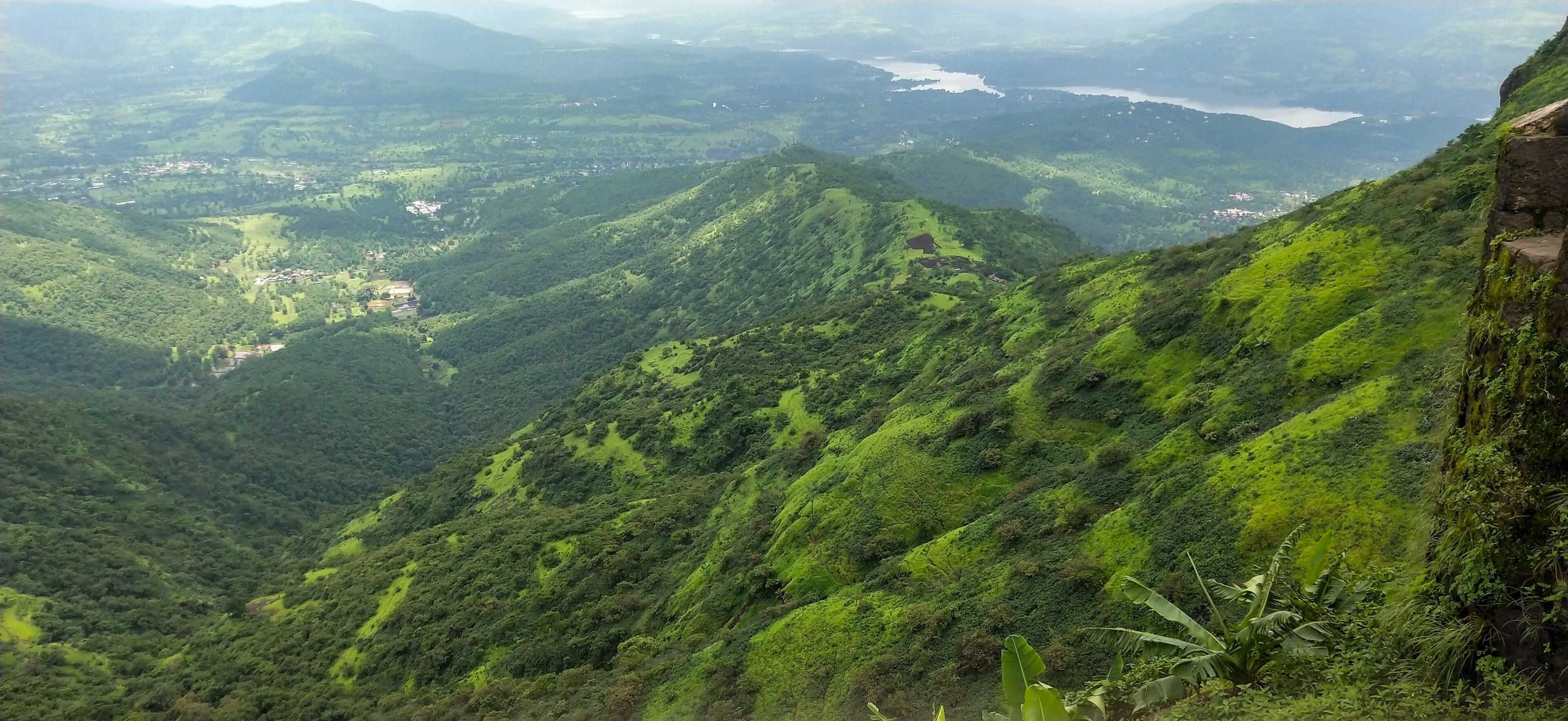 A lush green valley with a river and a distant lake.