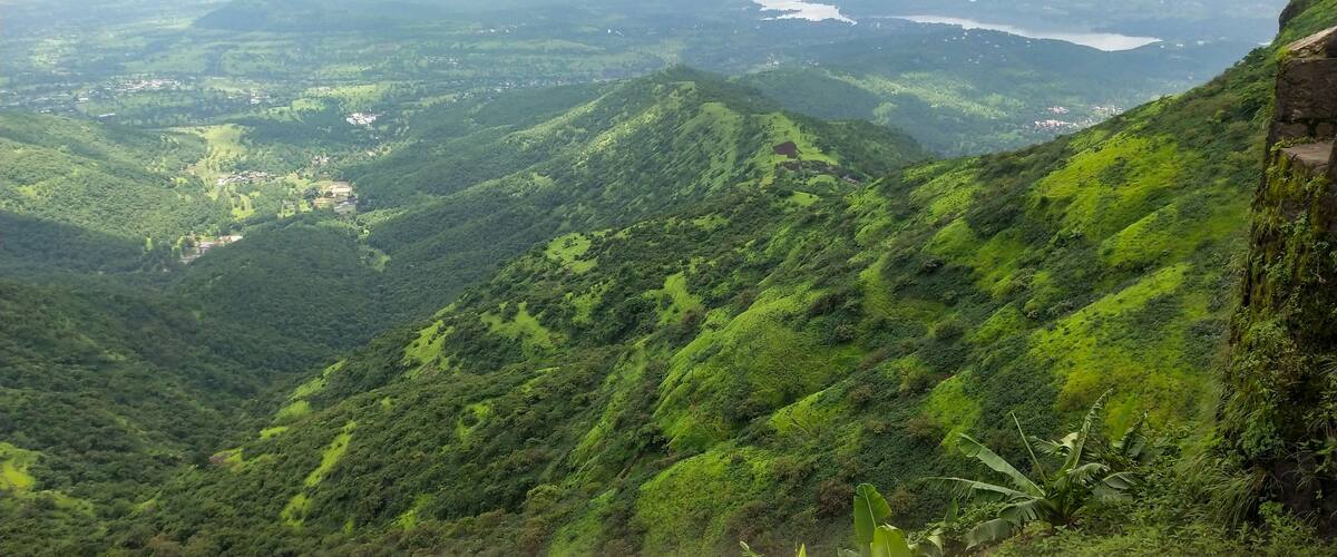 A lush green valley with a river and a distant lake.