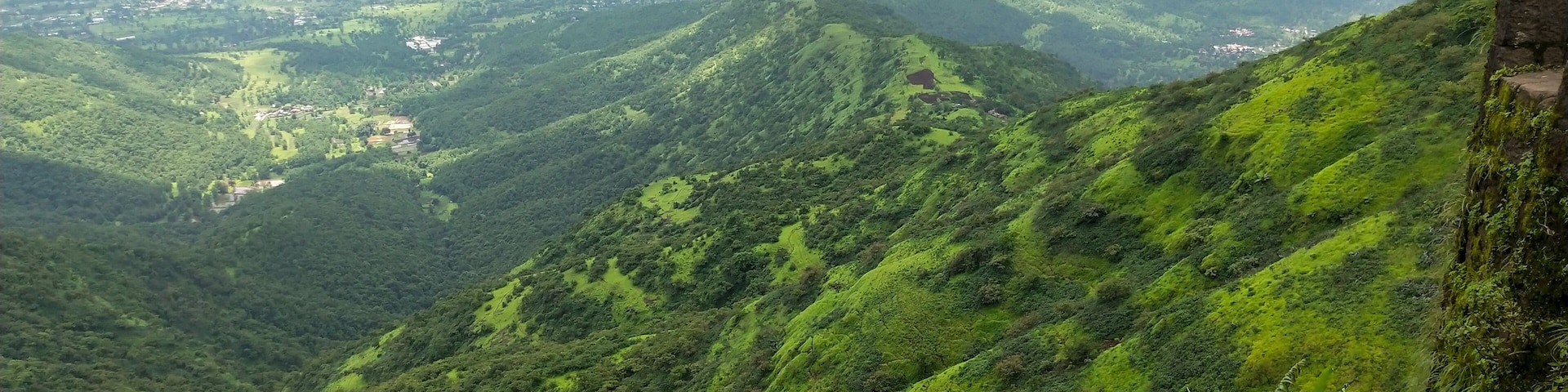 A lush green valley with a river and a distant lake.