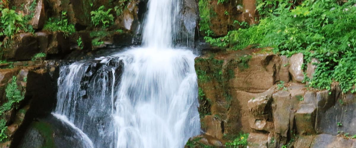 A waterfall cascading over rocky terrain with lush greenery.