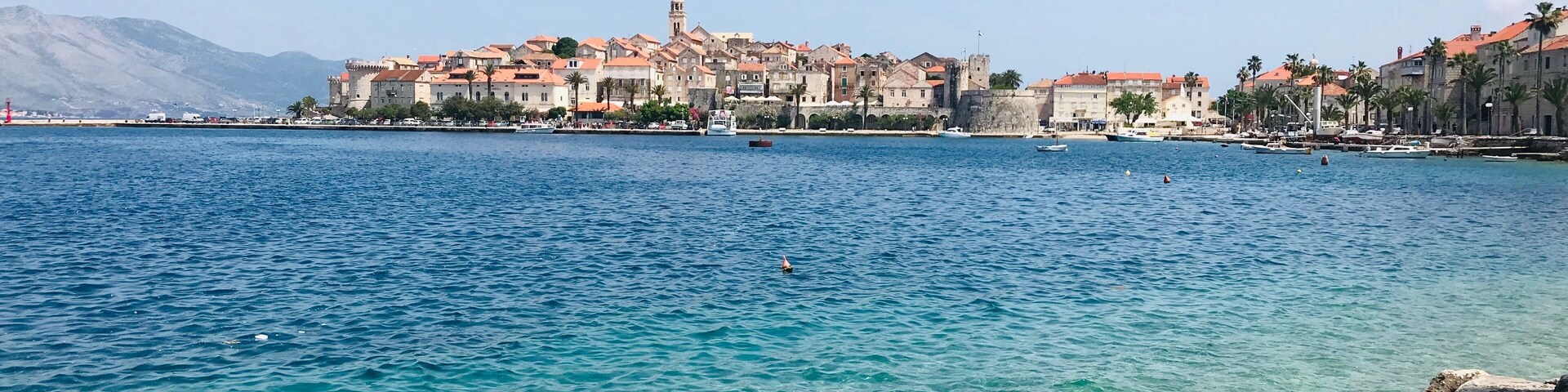 Un pueblo costero con edificios históricos y un mar azul cristalino.