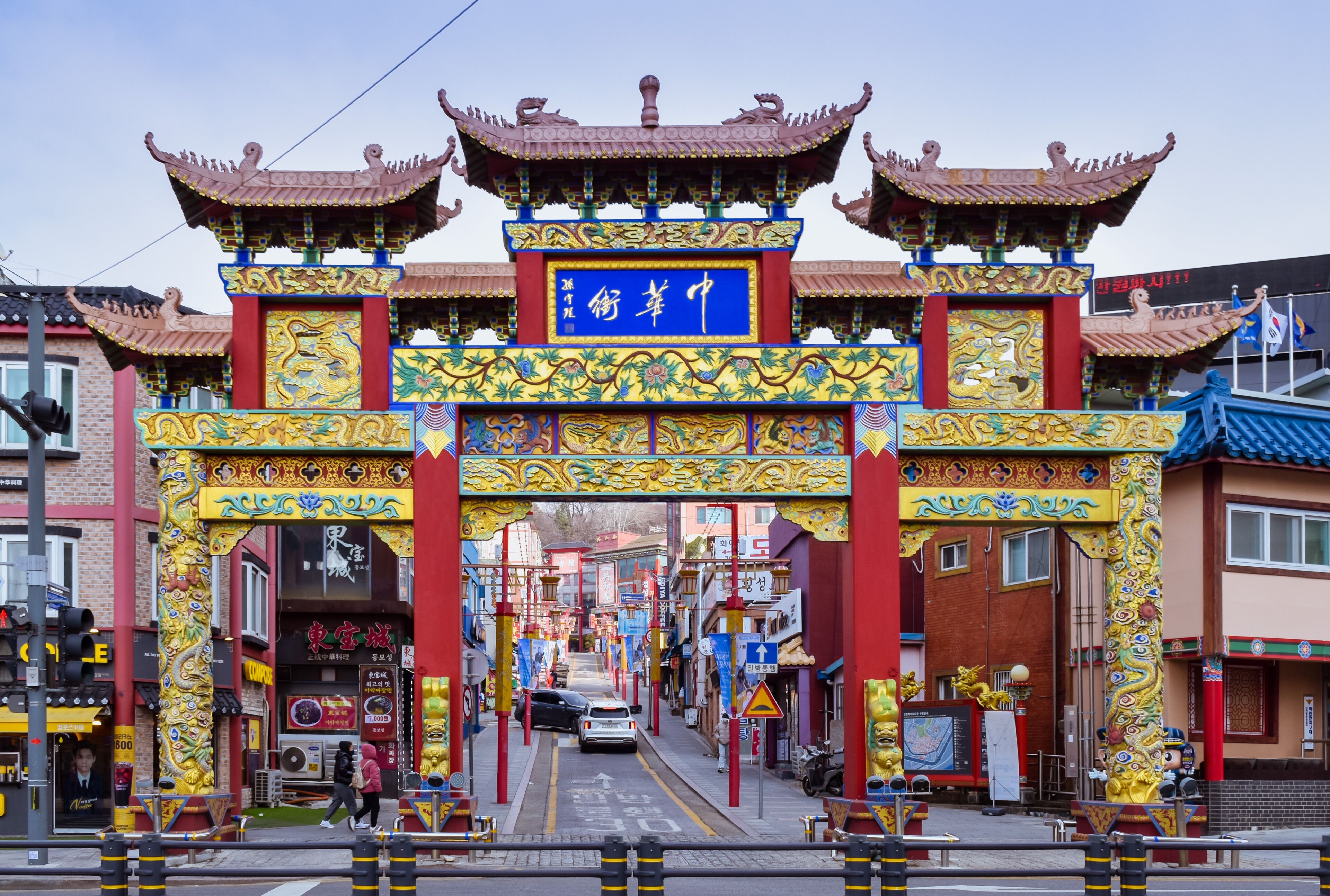 Una puerta tradicional china con decoraciones elaboradas y un letrero azul.