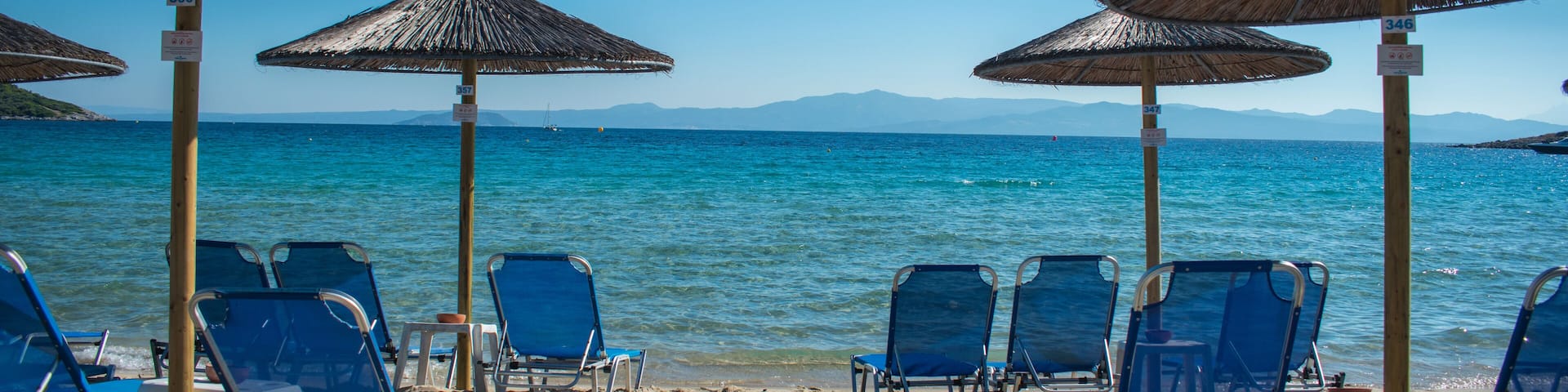 Sun chairs on the beach with sea in background. Summer holiday / vacation. Xenia Golden Beach, Paliouri, Chalkidiki, Greece on a beautiful summer day