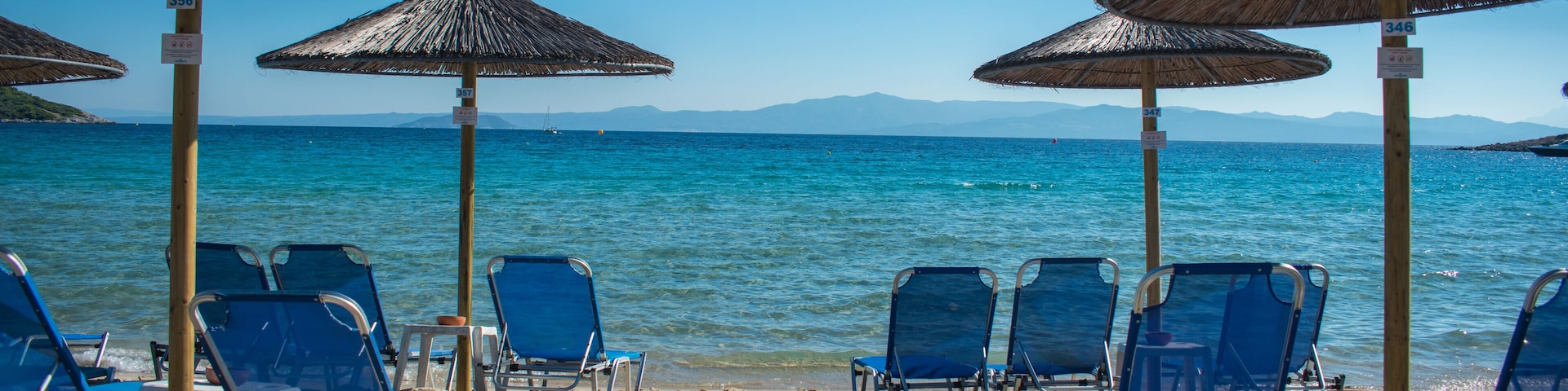 Sun chairs on the beach with sea in background. Summer holiday / vacation. Xenia Golden Beach, Paliouri, Chalkidiki, Greece on a beautiful summer day