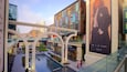 A modern shopping mall with a central water feature, glass railings, and various stores.