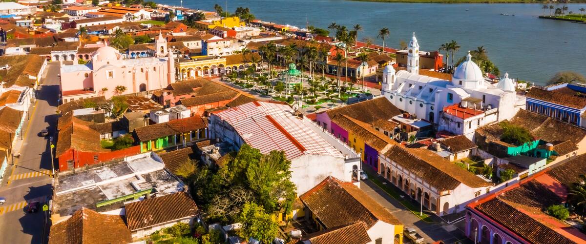 A coastal town with colorful buildings, a river, and a large white church with a dome.