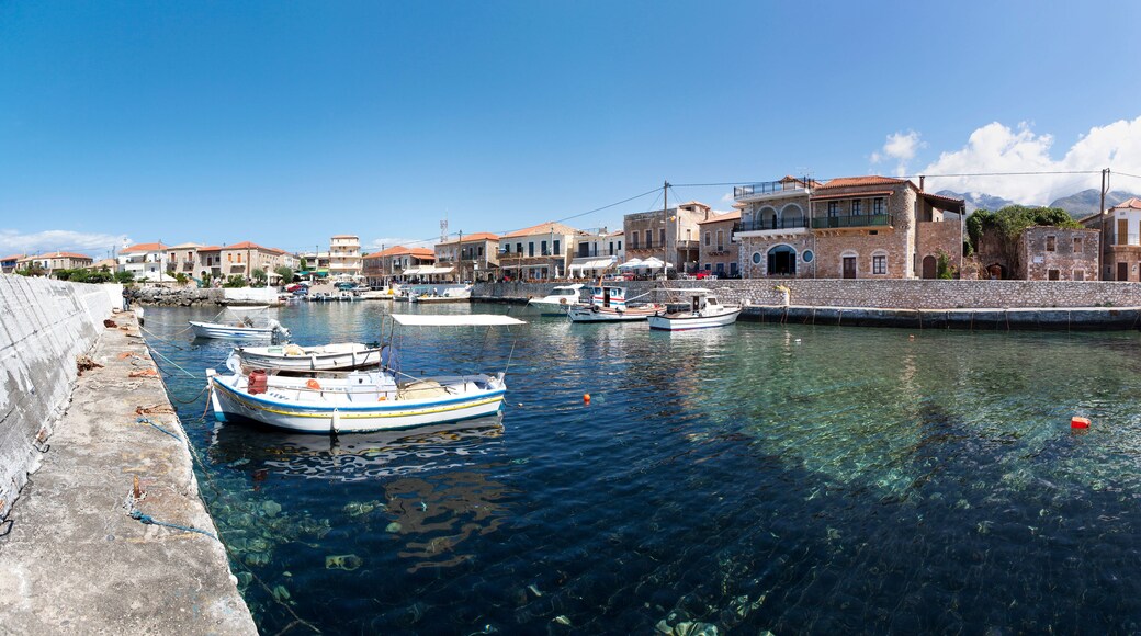 A harbor with boats docked, stone buildings, and clear blue water.