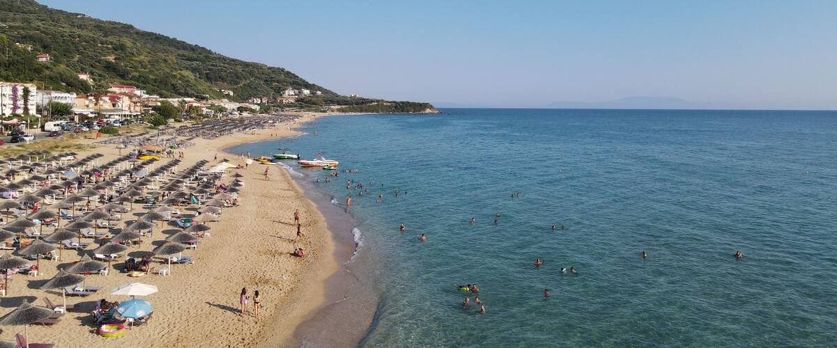 A beach with umbrellas and people swimming.