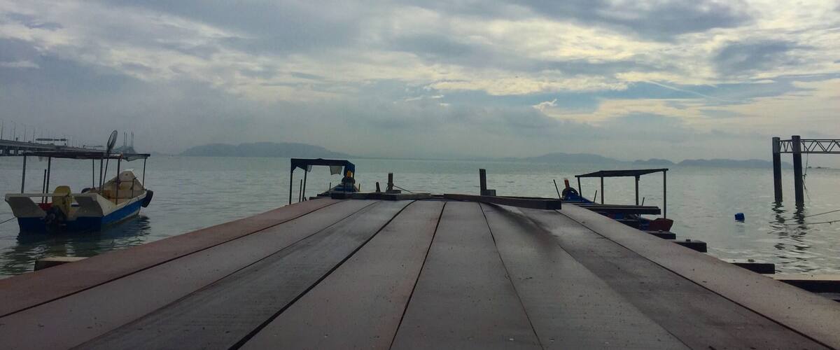 A wooden pier extending into calm water with boats docked on either side.