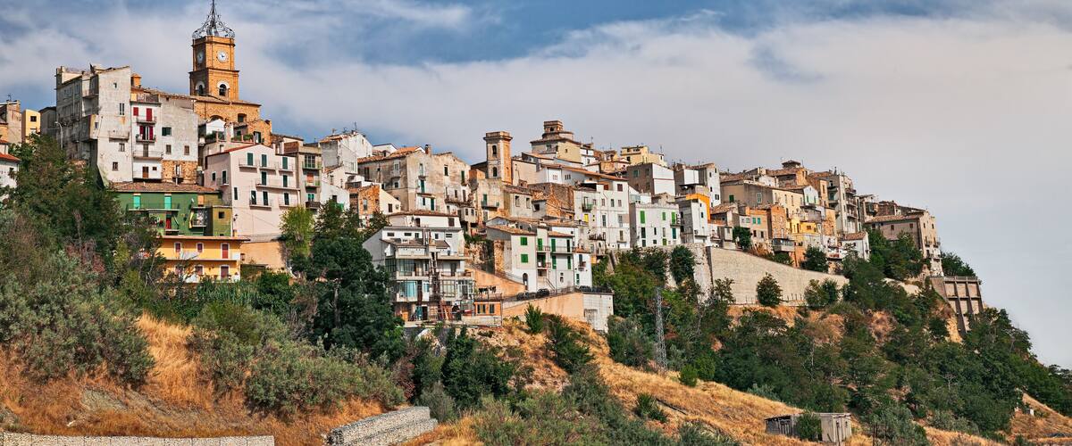 A hillside town with colorful buildings and a prominent clock tower.