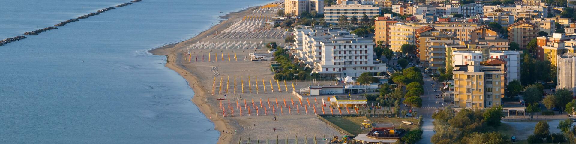 Drone view of sandy beach with umbrellas and town background
