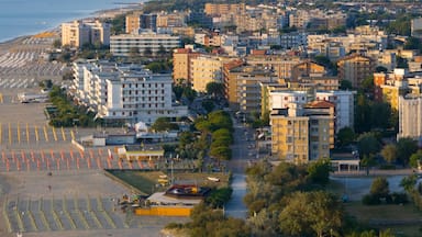 A coastal cityscape with a beach, buildings, and a breakwater.