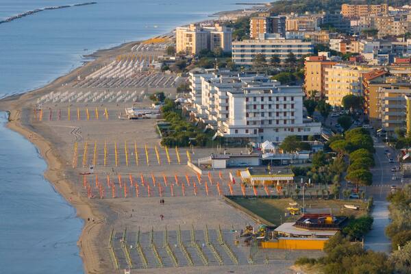Drone view of sandy beach with umbrellas and town background