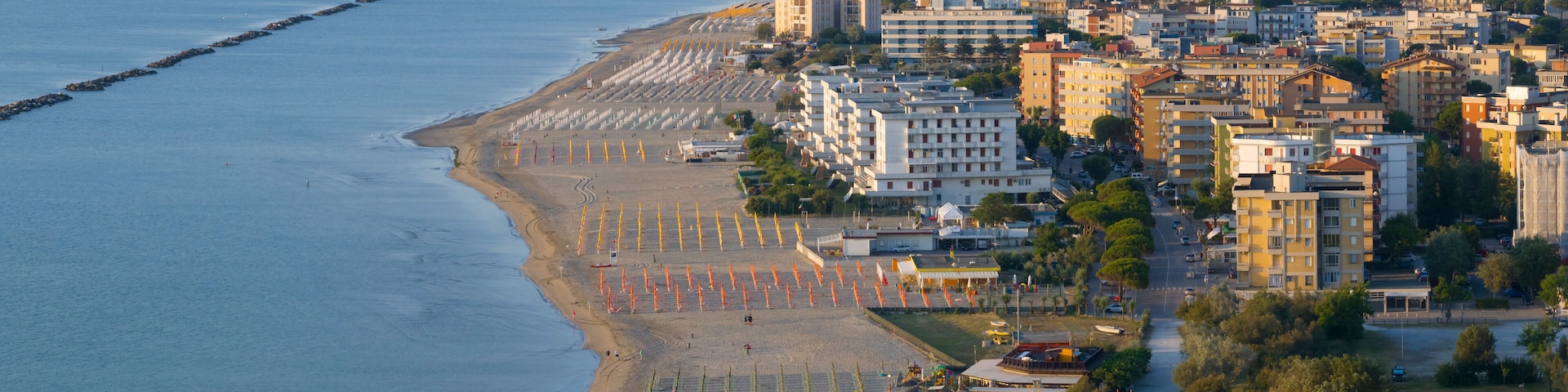 Drone view of sandy beach with umbrellas and town background