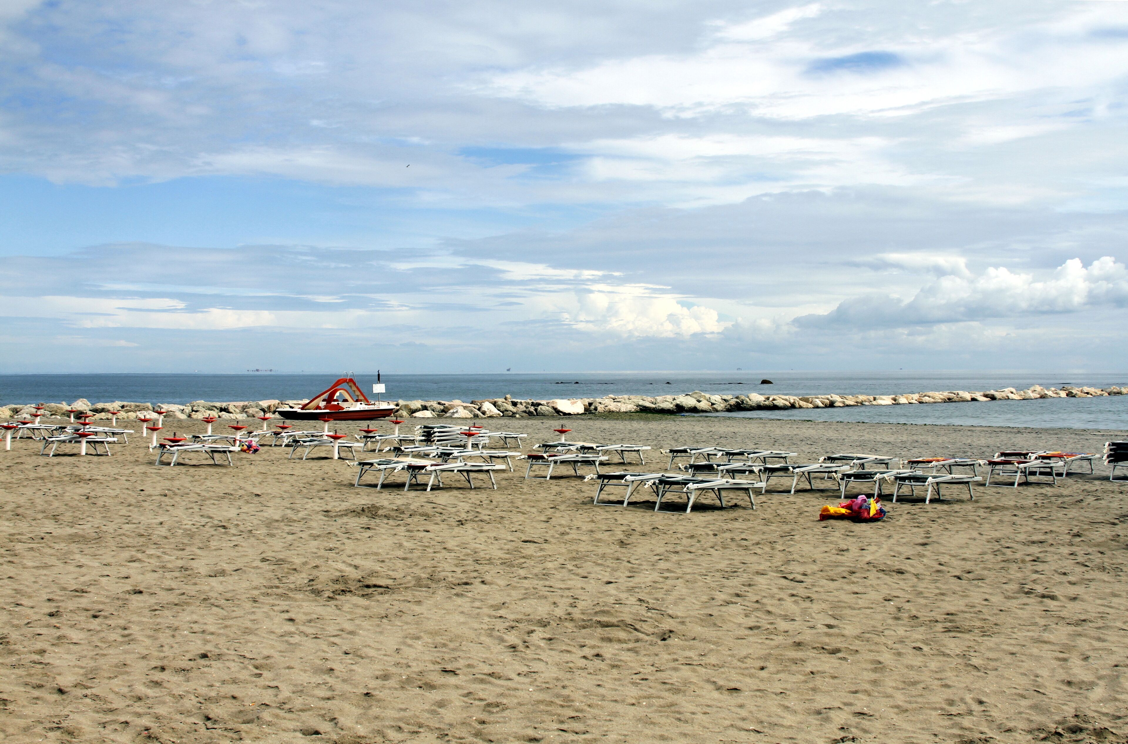 A sandy beach with numerous sun loungers and a lifeguard tower.