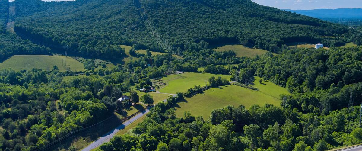 A lush green valley with rolling hills, a winding road, and a distant power line tower.
