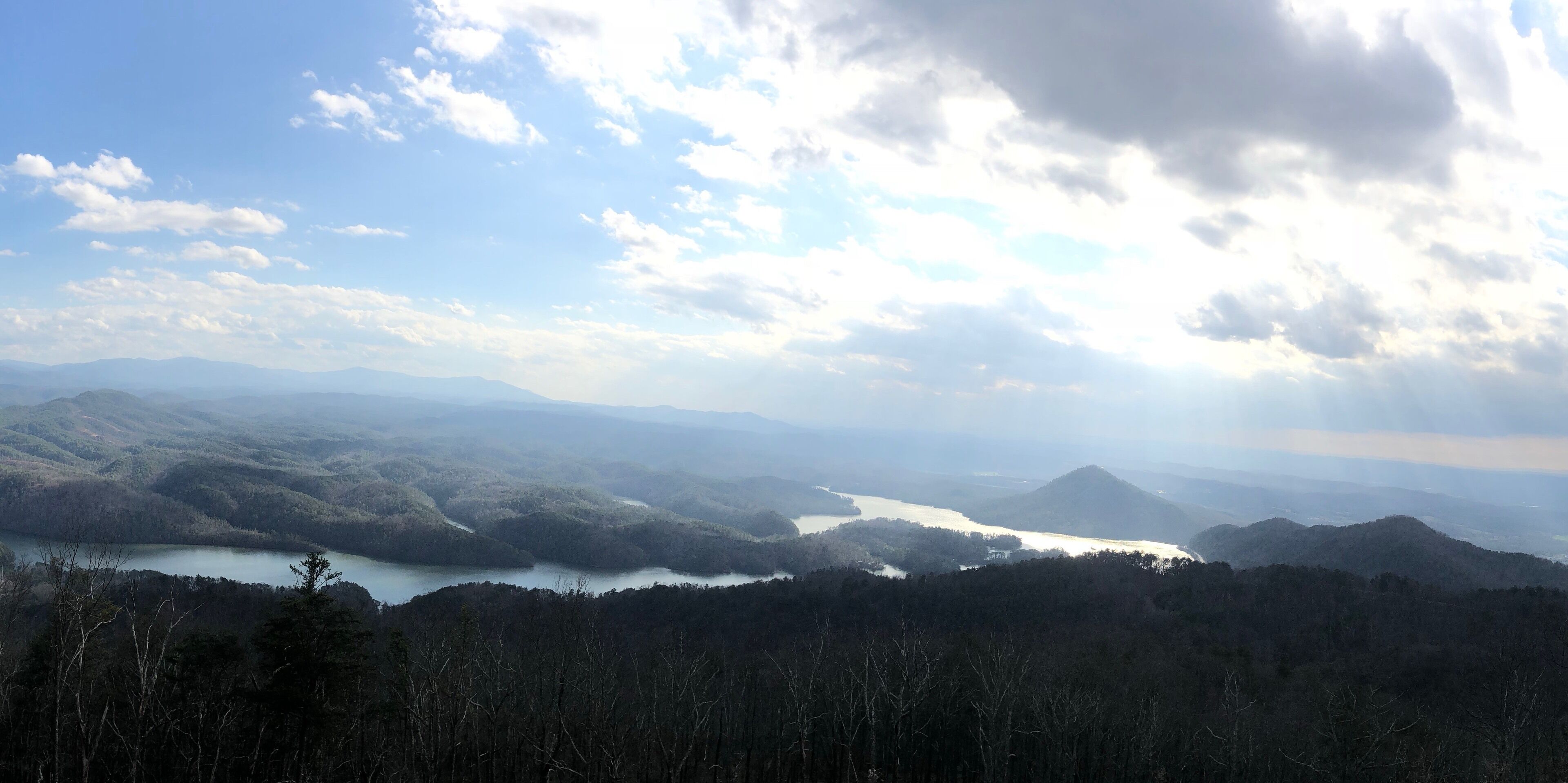 A mountainous landscape with a lake and forested hills.