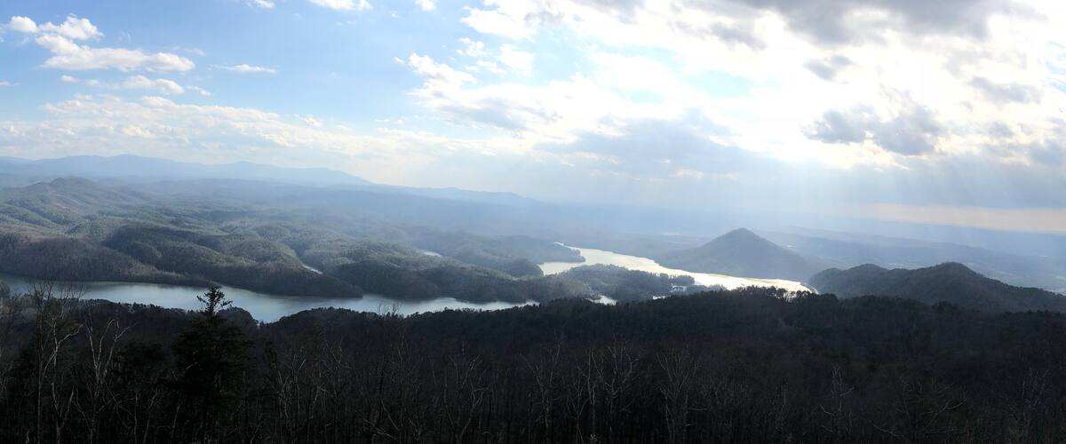 A mountainous landscape with a lake and forested hills.