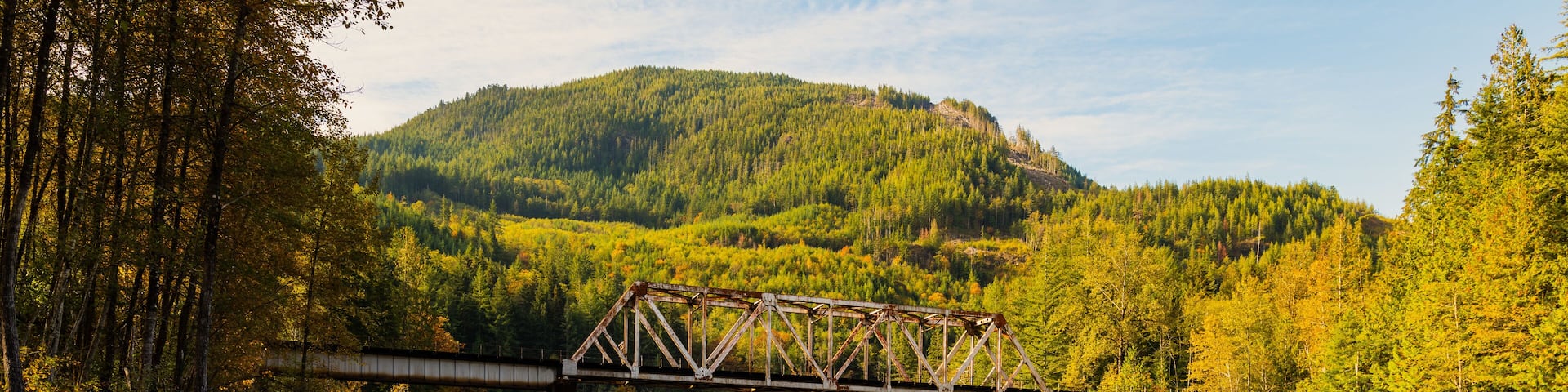 Skykomish River reflecting the railway bridge as the trees begin to turn fall colors in Western Washington State