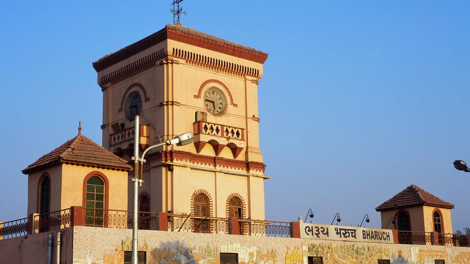 A historic building with a clock tower, a mural, and a sign in a foreign language.