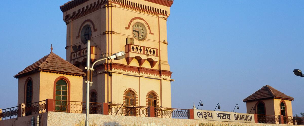 A historic building with a clock tower, a mural, and a sign in a foreign language.