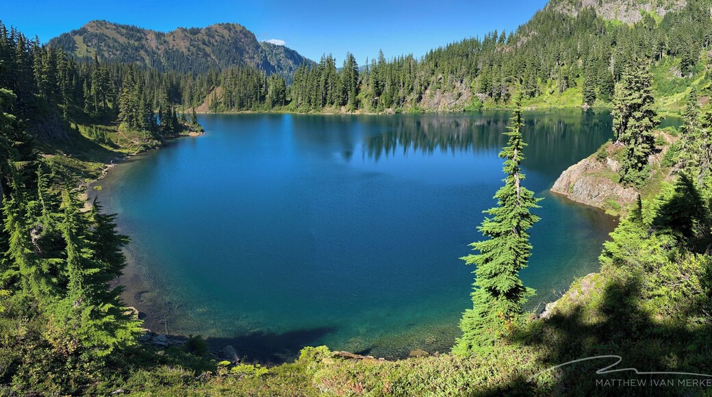 The Chain Lakes trail is a 5.6 mile loop with a vertical gain of 1,820 feet, offering stunning views of Mt. Shuksan and Mt. Baker in Washington's North Cascades. The trail skirts several lakes including the largest, Iceberg Lake.