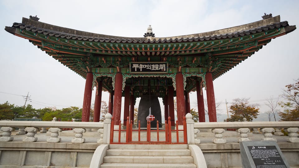A traditional Korean pavilion with ornate green and red roof, a stone staircase leading up, and a plaque in front.