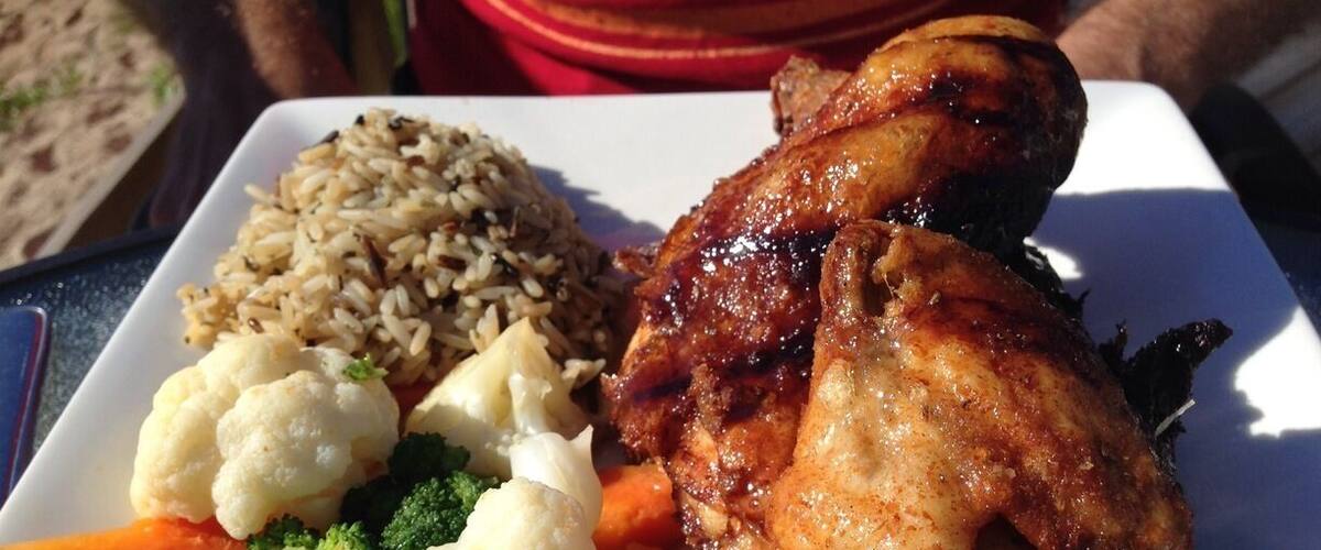 A plate of food with roasted chicken, rice, and vegetables.