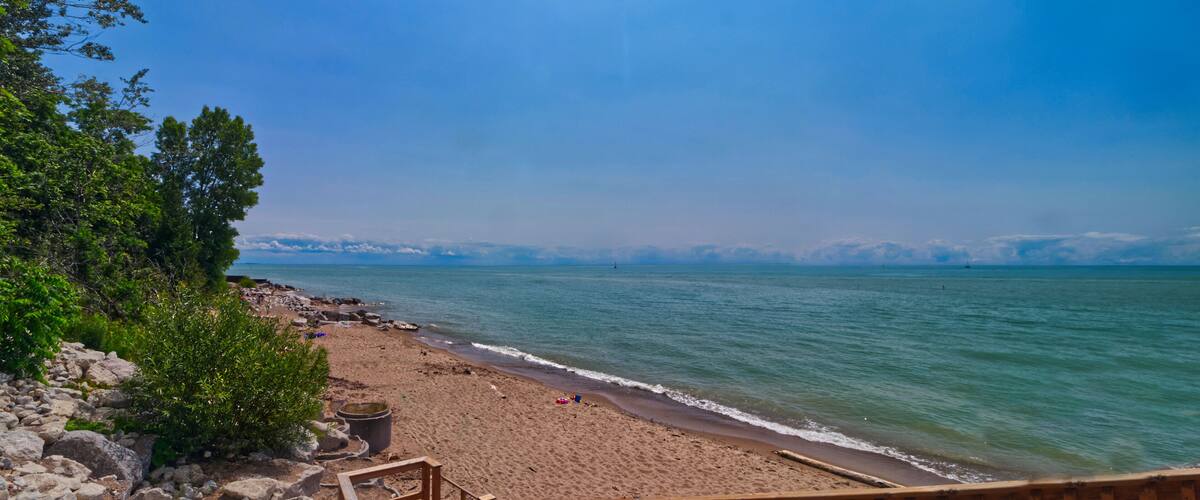 A beach with a wooden deck, rocky shoreline, and calm waters.